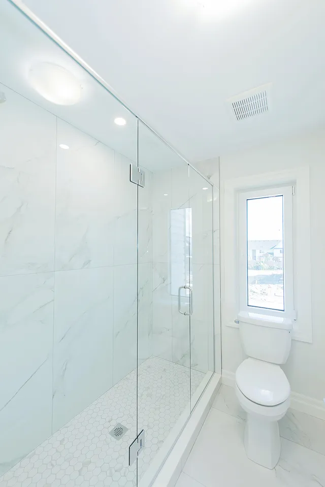 Shower in marble-look porcelain with a window and a glass door