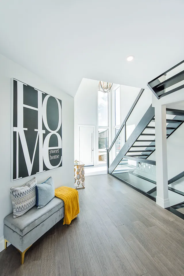 Foyer with a black steel stair, glass balustrade and grey plank flooring