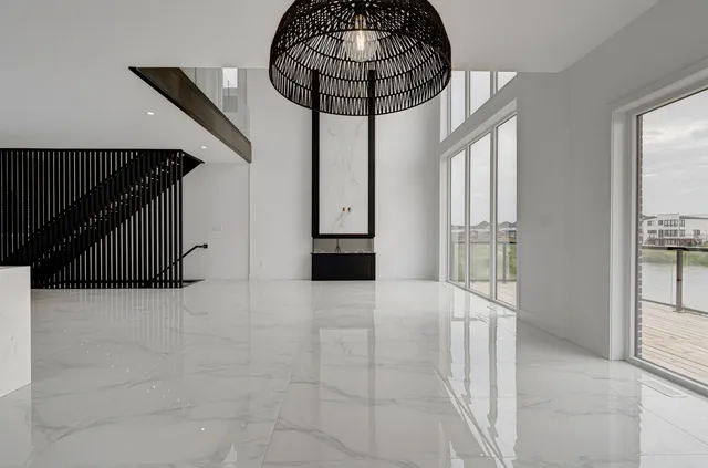 Great room with a polished marble-look porcelain floor, a black vertical slat stair screen and a rattan pendant