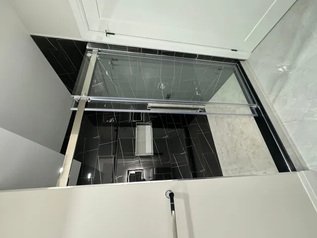 Black marble-look porcelain shower walls behind a glass screen