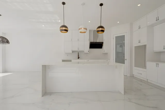 Kitchen with white cabinets, gold pendants and a polished porcelain floor