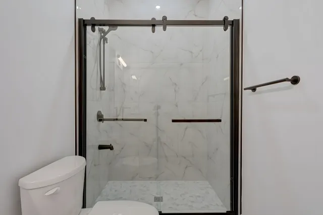Bathroom with a marble-look porcelain shower and dark hardware