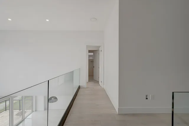 Upper landing with grey plank flooring and a glass balustrade