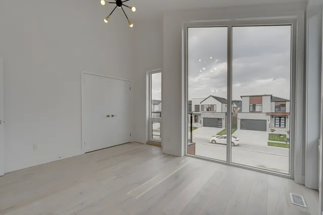 Room with grey plank flooring, a black pendant and sliding doors